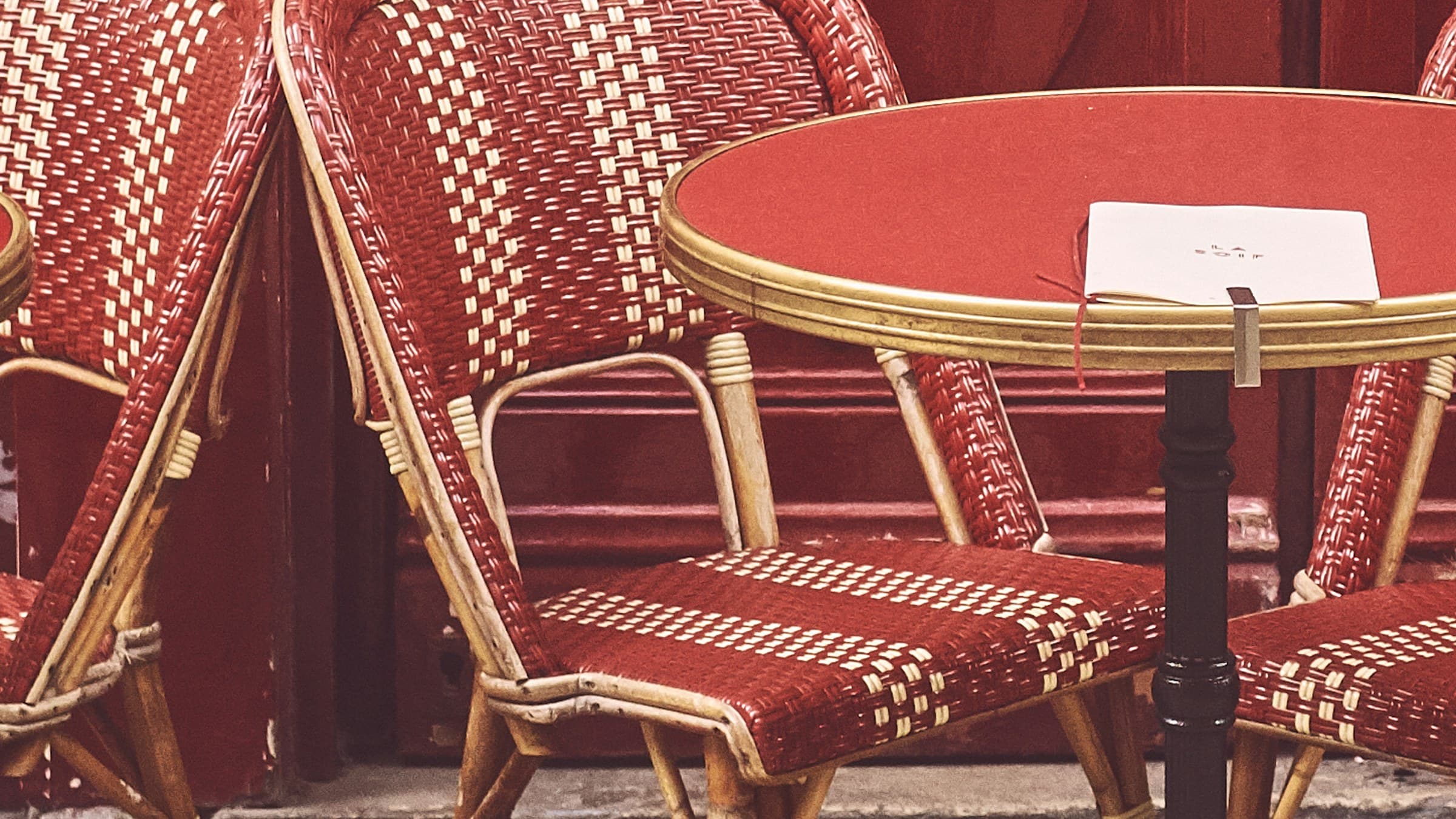 Terrasse parisienne avec chaises rouges classiques et tables dressées